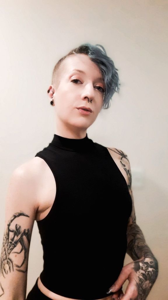 Kae Audhild modeling Prozis black Smoothie tank top, fitness model, mock neck cropped length sleeveless fashionable activewear for women, tattooed fashion social media influencers internet models nonbinary afab women with blue hair undercuts