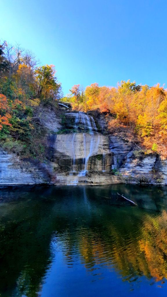 Chequaga Shequaga Falls in Montour Falls NY October 2024 orange autumn foliage reflected on water below a beautiful waterfall, photo by Kae Audhild travel blogger