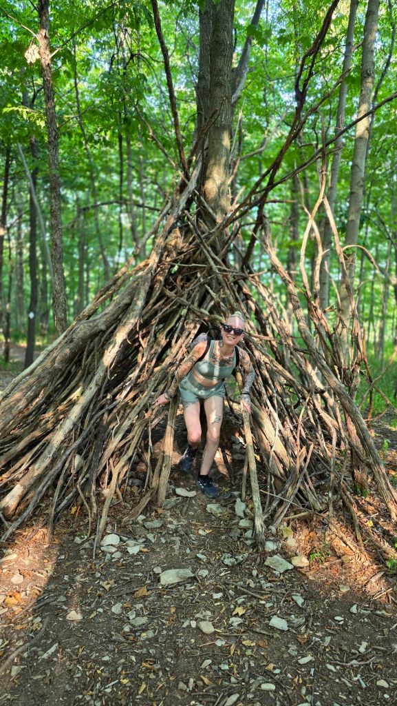 Kae Audhild playing in a simple stick hut in the forest at Three Falls Woods in Manlius, NY 