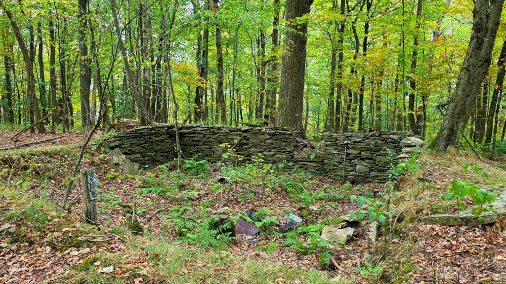 Old stone fountain and rusted metal farm items at Pettus Hill Preserve in Windsor, NY