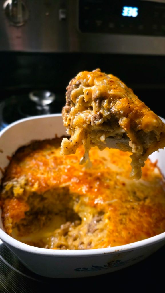Cozy cheeseburger casserole baked in a square dish, made with ground beef, egg noodles, and melted cheddar cheese for an easy winter dinner.