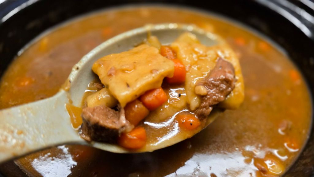 Cozy homemade beef stew with rustic flat dumplings and vegetables, photographed close up.